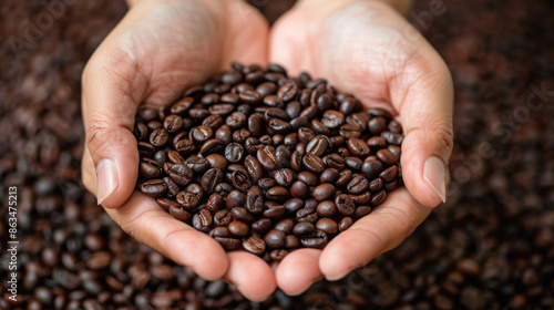 A hand is holding a handful of coffee beans. The beans are small and brown, and they are spread out in a pile. Concept of warmth and comfort