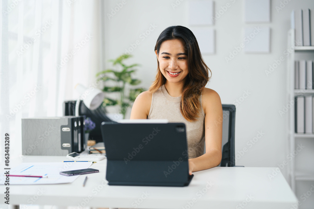Confident Asian Business Woman Working on Tablet in Modern Office Setting with Bright Natural Light Confident Asian Business Woman Working on Tablet in Modern Office Setting with Bright Natural Light
