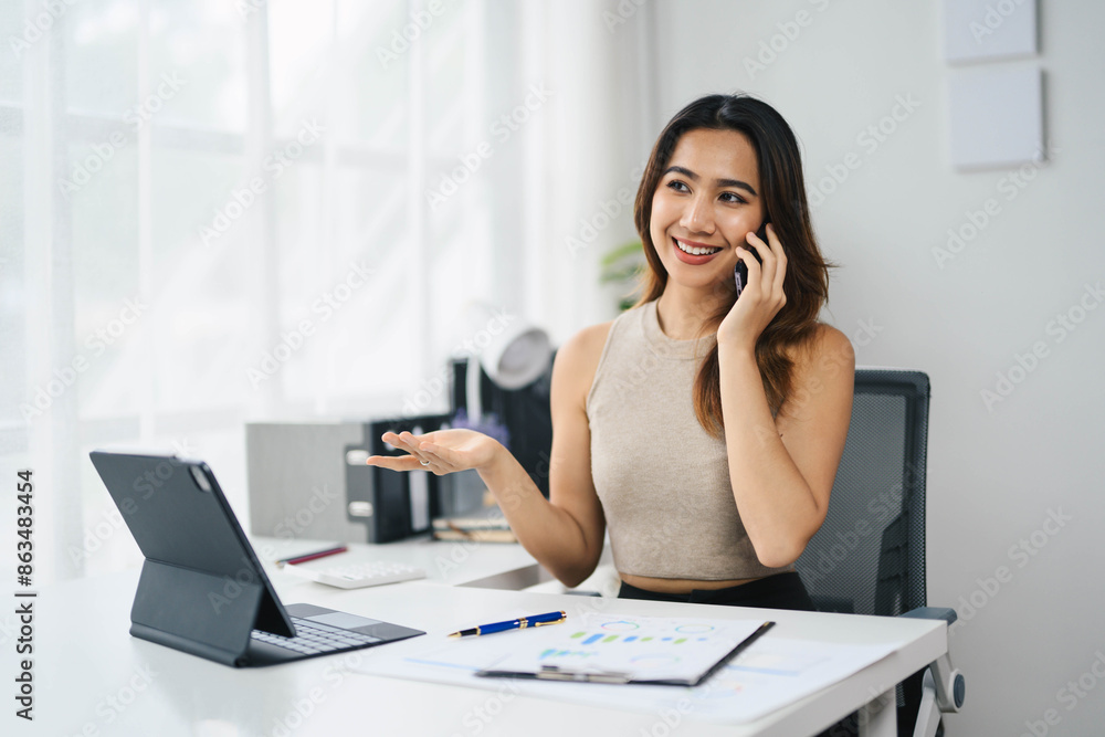 Confident Asian Business Woman Working on Tablet and Talking on Phone in Modern Office Environment Confident Asian Business Woman Working on Tablet and Talking on Phone in Modern Office Environment