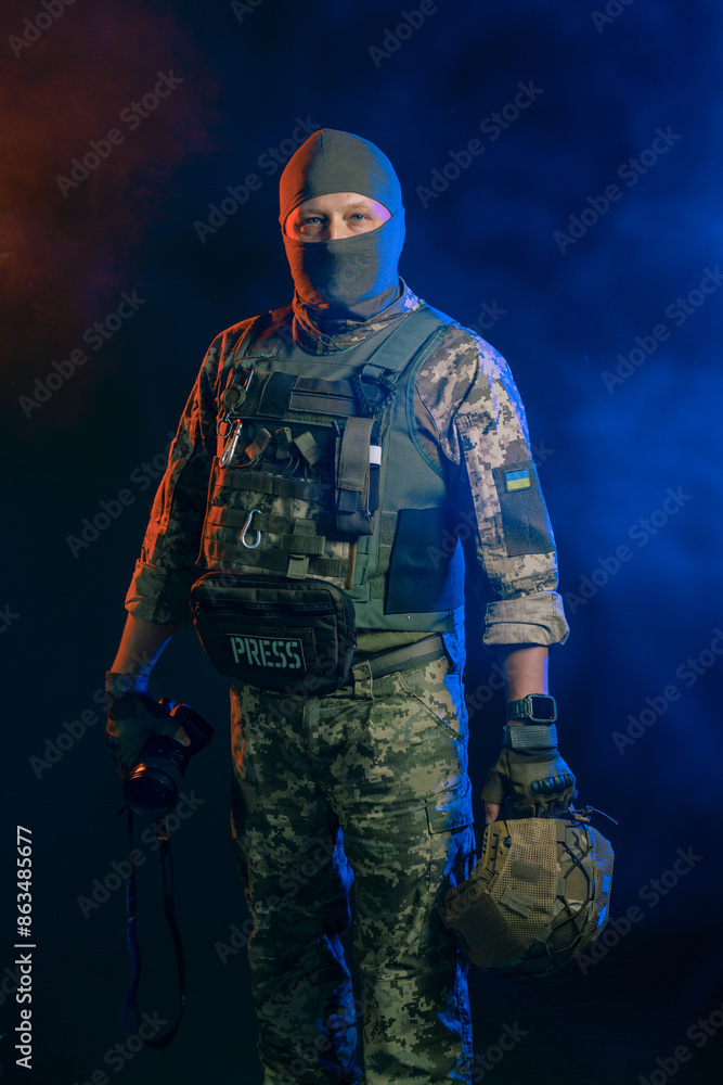 Fototapeta premium Military reporter in tactical uniform with a camera in his hands on a dark background