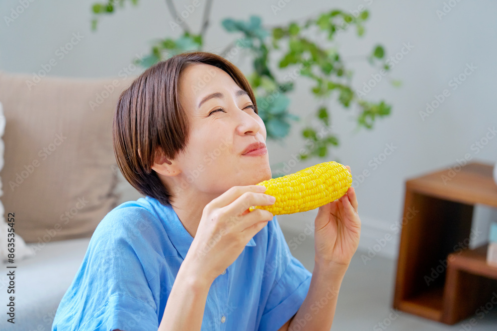 自宅でとうもろこしを食べる女性 自宅でとうもろこしを食べる女性