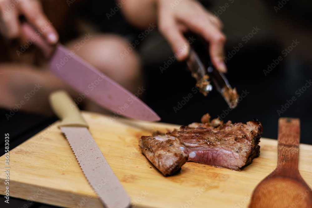 close up woman hands use a knife to cuting the grill meat streak in camp ground, close up woman hands use a knife to cuting the grill meat streak in camp ground,