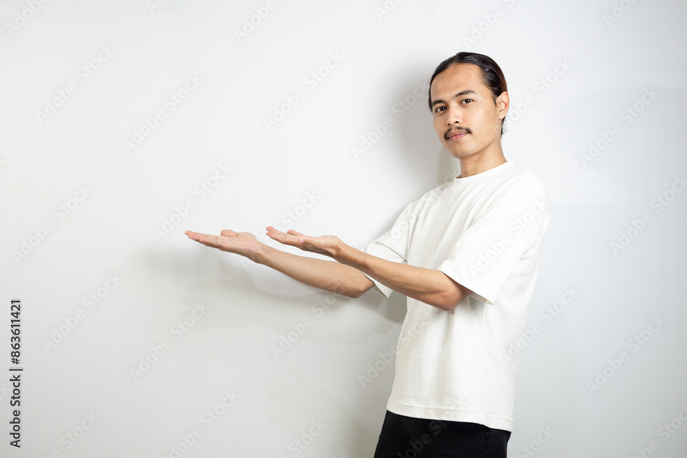 Asian man in white t-shirt pointing to the side. isolated on white studio background. Asian man in white t-shirt pointing to the side. isolated on white studio background.