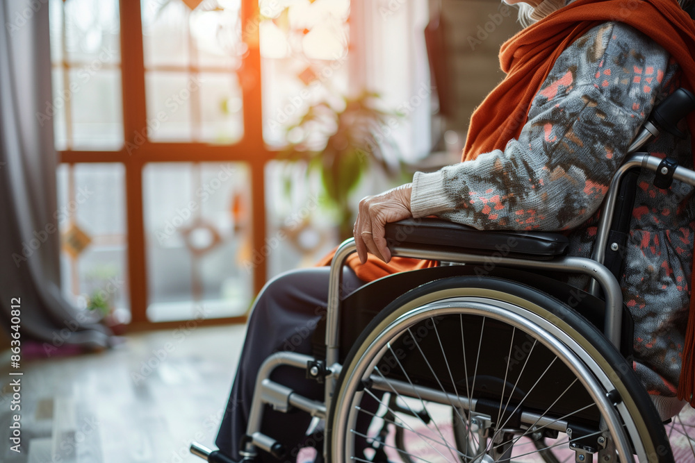 Obraz premium person in a wheelchair is sitting in a living room. The room is furnished with a couch and a potted plant. The atmosphere of the image is calm and peaceful