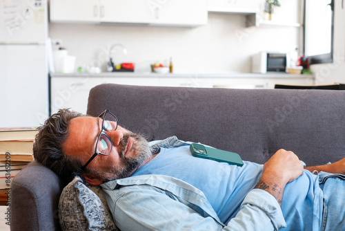 Fotografie Exhausted man fell asleep on the comfortable sofa in the modern living room, without energy after a hard day at work
