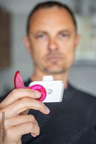 Close up view of man using medicine dry powder inhaler for treatment asthma or COPD diseases. Pharmaceutical product is used to treat lung inflammation and prevent asthma attack. photo