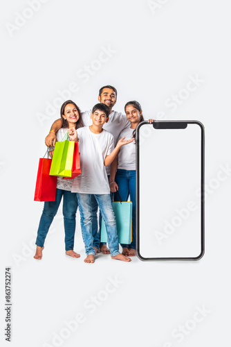 asian Indian family promoting sale offer standing with big tall smartphone cutout