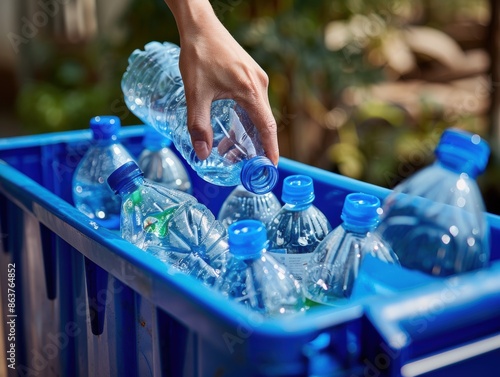Wallpaper Mural A close-up of a hand placing a plastic bottle into a blue recycling bin, symbolizing individual efforts in environmental conservation and waste management.
 Torontodigital.ca