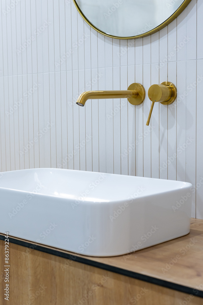 Bronze bathroom water tap in a bathroom finished with white tiles. Minimalist bathroom finish. Photographed in natural light.