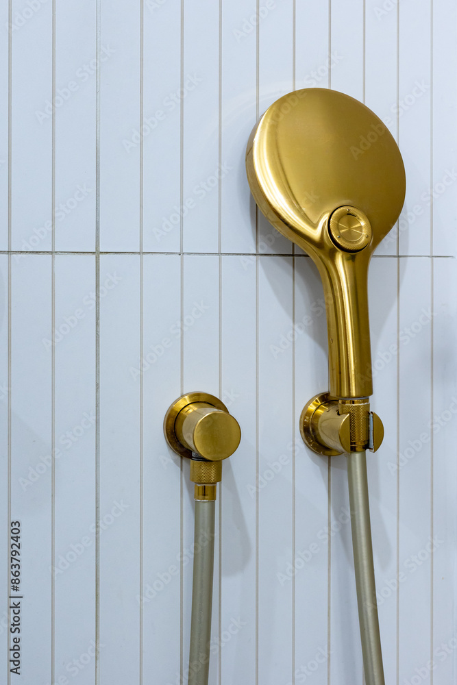 Bronze, braas bathroom handshower in a bathroom finished with white tiles. Minimalist bathroom finish. Photographed in natural light.