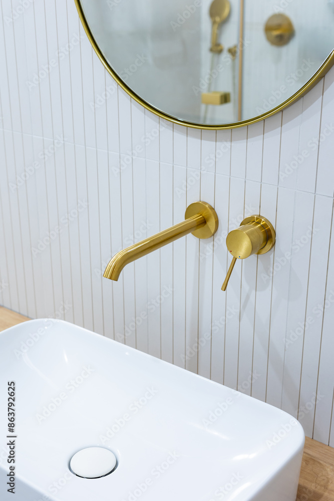 Bronze bathroom water tap in a bathroom finished with white tiles. Minimalist bathroom finish. Photographed in natural light.