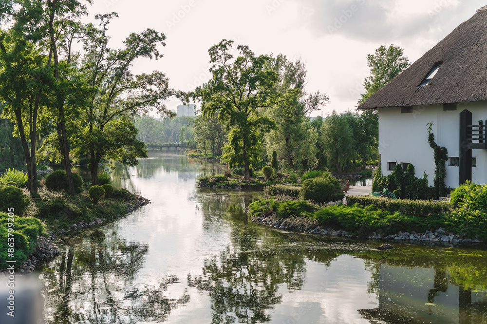 Landscape in a city park, lake, river and cottages against the backdrop of a lawn and beautiful landscaping with stones Landscape in a city park, lake, river and cottages against the backdrop of a lawn and beautiful landscaping with stones