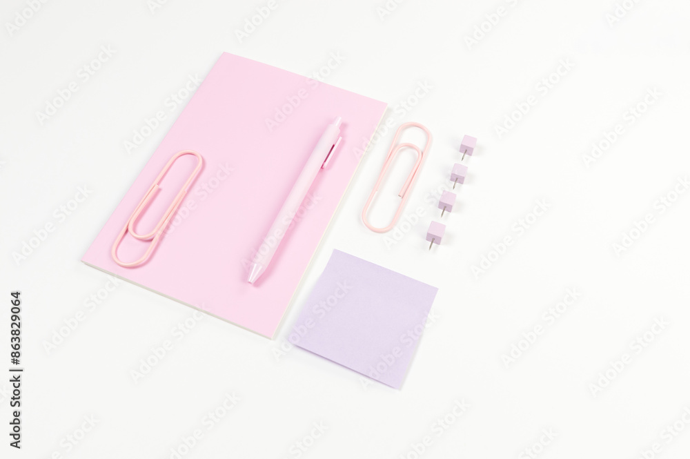 Top view of pink notebook on white background. Sticky note, paperclips, pen and pins. School, office wallpaper. Flat lay, copy space. Top view of pink notebook on white background. Sticky note, paperclips, pen and pins. School, office wallpaper. Flat lay, copy space.