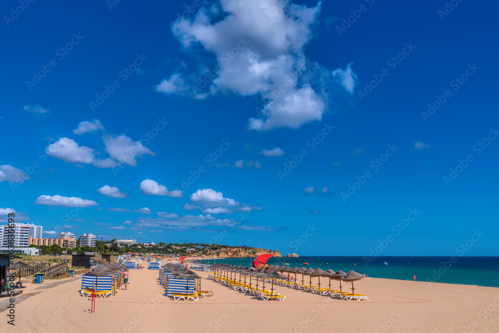 Obraz premium Alvor Portugal beautiful sandy beach with umbrellas and sun loungers the Algarve between Portimao and Lagos