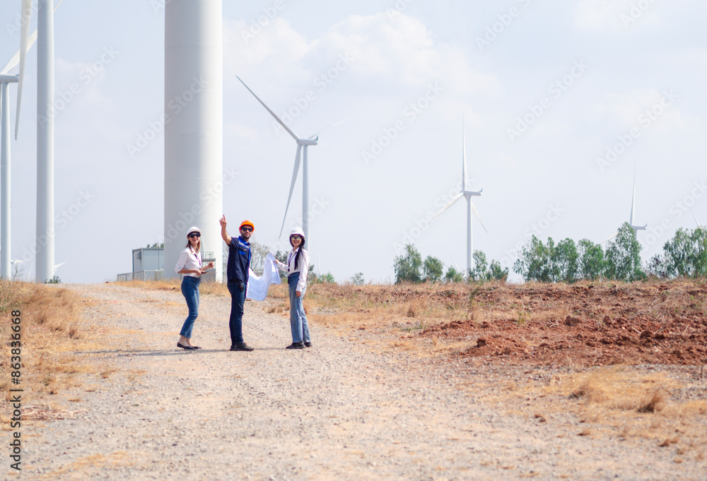 Group of engineers and architects working on the basis of a wind turbine Inspect the structure with the wind turbine in the background. Group of engineers and architects working on the basis of a wind turbine Inspect the structure with the wind turbine in the background.