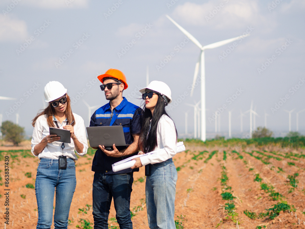 Group of engineers and architects working on the basis of a wind turbine Inspect the structure with the wind turbine in the background. Group of engineers and architects working on the basis of a wind turbine Inspect the structure with the wind turbine in the background.