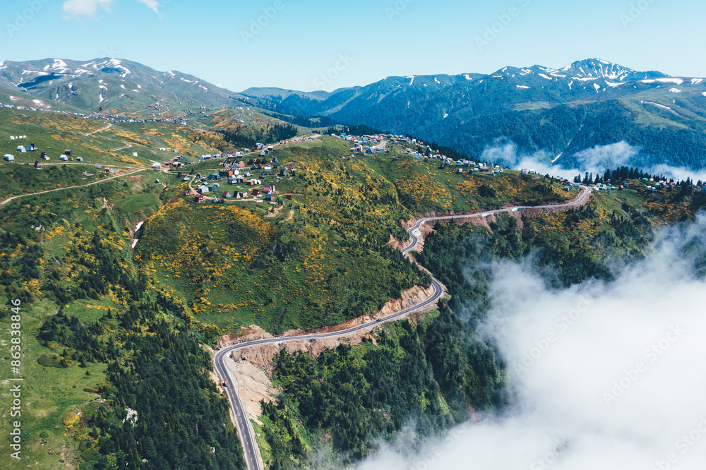 Aerial Drone view of Gomismta village, secluded mountain resort in Georgia, nestled above clouds in Guria region, green landscapes and winding roads leading through serene alpine environment. Aerial Drone view of Gomismta village, secluded mountain resort in Georgia, nestled above clouds in Guria region, green landscapes and winding roads leading through serene alpine environment.