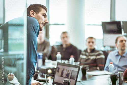 Business man making a presentation at office. Business executive delivering a presentation to his colleagues during meeting or in-house business training, explaining business plans to his employees.