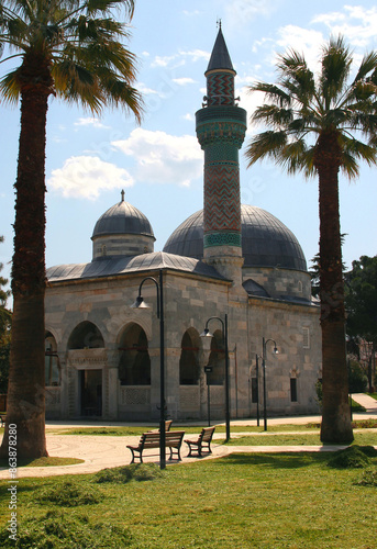 Photo with a view of the Yesil Camii mosque with a green minaret surrounded by tall palm trees in the historic part of Iznik, Turkey photo