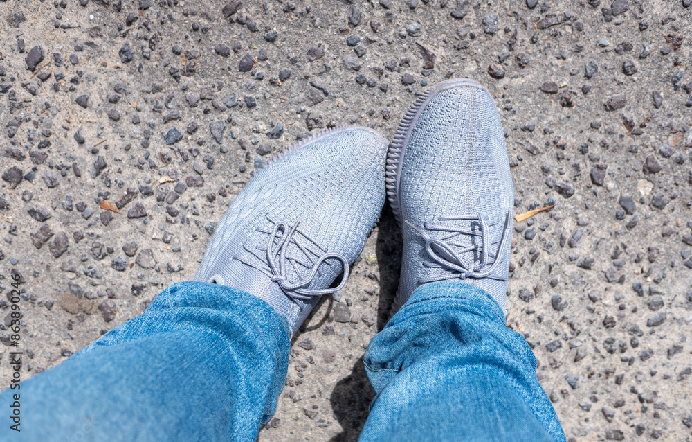 Feet in sneakers and jeans, top view of the ground. Feet in sneakers and jeans, top view of the ground.