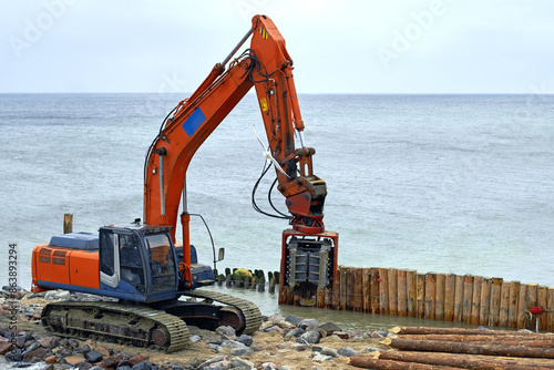 Pile driving machine on the beach on the seashore. Shoreline stabilization works
