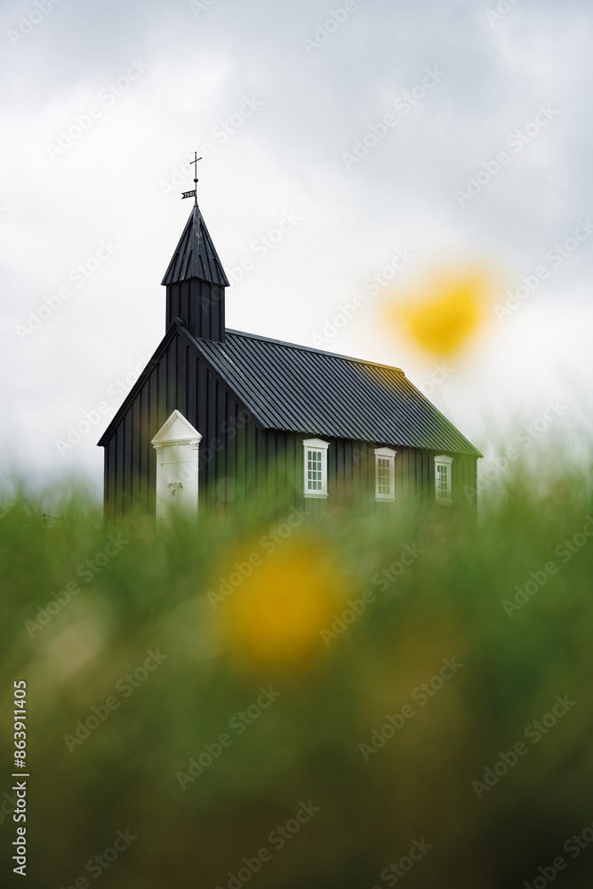Stunning view of the black church of Budir with defocused grass in the foreground. Búðakirkja is a small wooden church located on the south side of Snæfellsnes, Iceland.