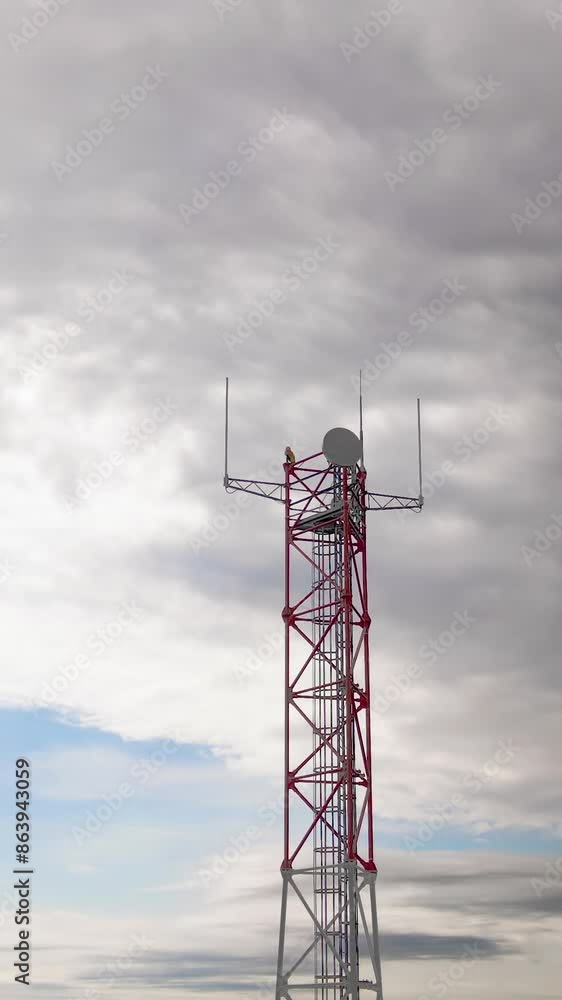 Vertical video. Mobile receiver and transmitter antenna tower, antenna tower building with the blue sky. Close-up of the antenna building or Communication antenna tower with the sky background Vertical video. Mobile receiver and transmitter antenna tower, antenna tower building with the blue sky. Close-up of the antenna building or Communication antenna tower with the sky background