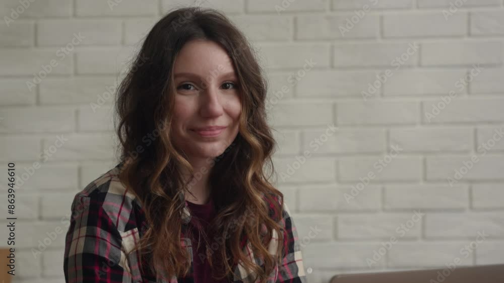 Indoor image showing a cheerful young woman in a plaid shirt with a relaxed and friendly vibe Indoor image showing a cheerful young woman in a plaid shirt with a relaxed and friendly vibe