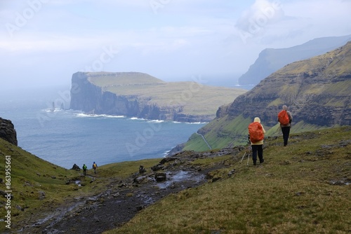 Mountain trip from Saksun village of Saksun to Tjornuvik on island of Streymoy. Silhouettes of hiking people on trail. Faroe Islands, Denmark