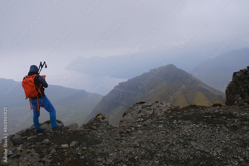 Fototapeta premium Silhouette of person on peak on foggy day. Eysturoy Island and climbing highest peak of Faroe Islands - Slættaratindur, Denmark. 