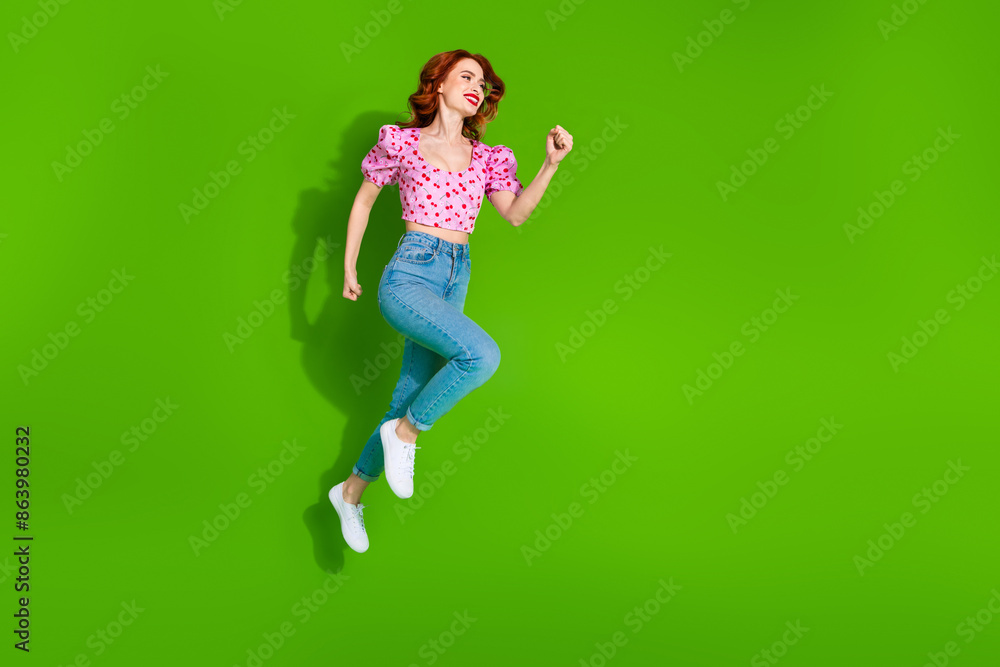 Full length photo of shiny attractive lady dressed print top jumping high running empty space isolated green color background Full length photo of shiny attractive lady dressed print top jumping high running empty space isolated green color background