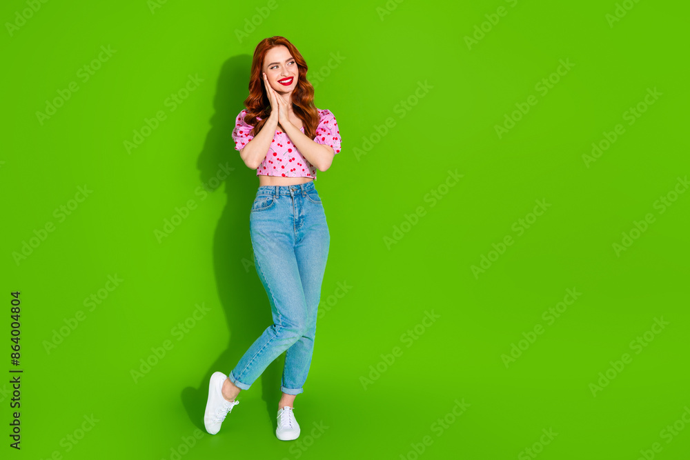 Full length photo of shiny attractive lady dressed print top arms cheek looking empty space isolated green color background Full length photo of shiny attractive lady dressed print top arms cheek looking empty space isolated green color background