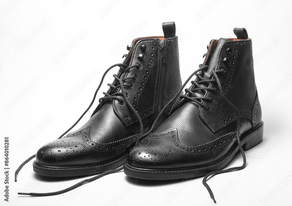 Stylish black leather men's brogue boots with untied laces on a white background Stylish black leather men's brogue boots with untied laces on a white background