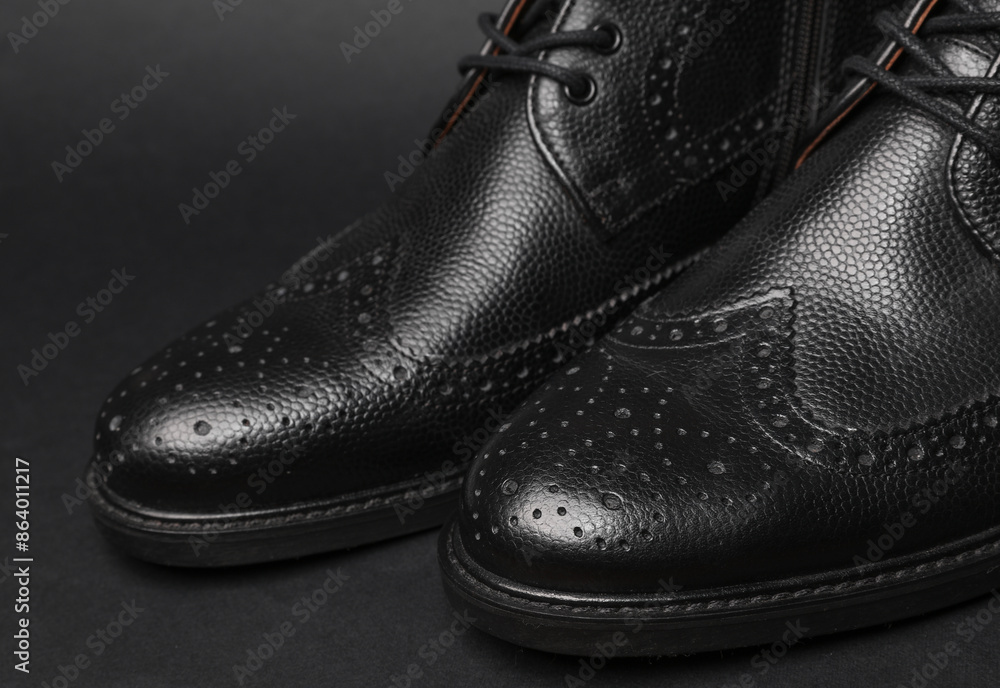 Stylish black leather men's brogue boots on a black background
