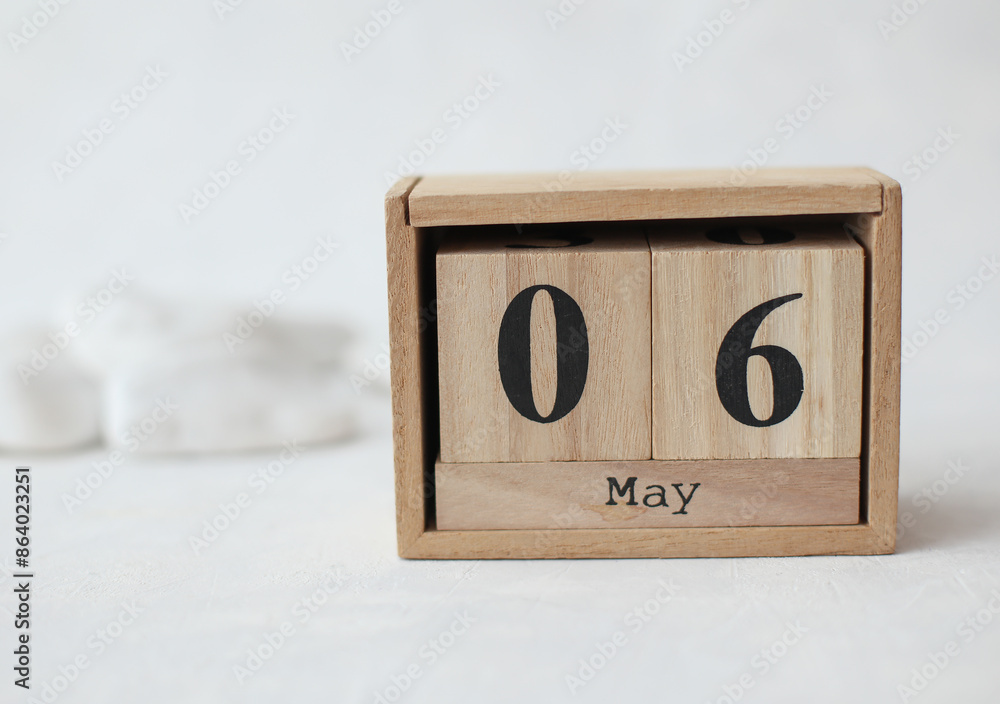Wooden block calendar with date May 6 on a concrete background with pebbles Wooden block calendar with date May 6 on a concrete background with pebbles