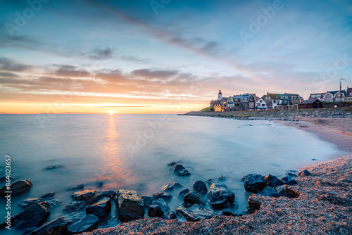 Sunset with a beautiful setting sun over the horizon near an old fishing village called Urk, with a heritage lighthouse
