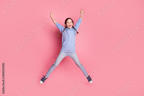 Full body portrait of cute little schoolkid jump raise fists wear hoodie isolated on pink color background © deagreez