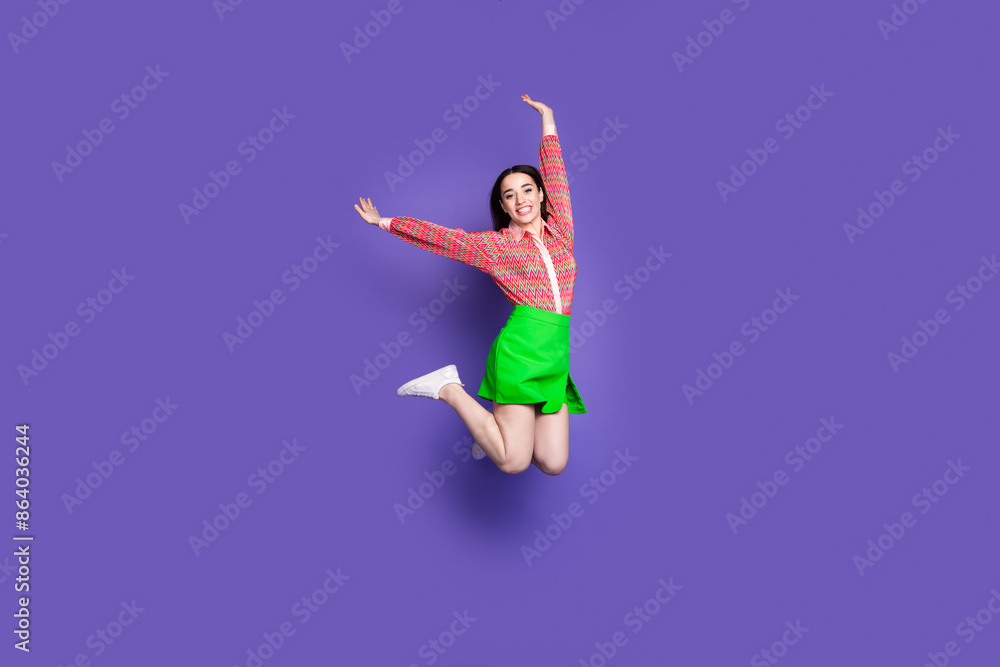 Full body photo of attractive young woman jump have fun dressed stylish pink clothes isolated on violet color background Full body photo of attractive young woman jump have fun dressed stylish pink clothes isolated on violet color background