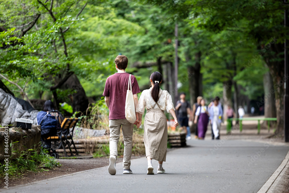 公園で手をつないで歩く若い男女 公園で手をつないで歩く若い男女