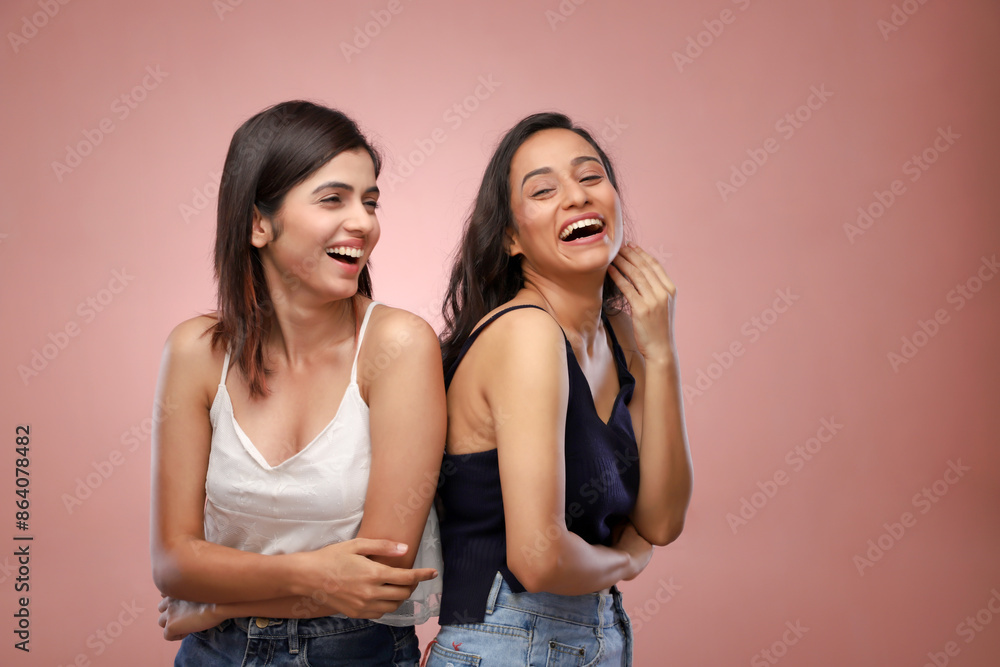 Two Amazing Women Laughing While Standing Over A Pink Background Two Amazing Women Laughing While Standing Over A Pink Background