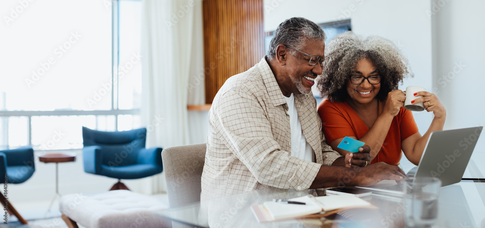 Mature couple doing online banking together, smiling and enjoying their time Mature couple doing online banking together, smiling and enjoying their time
