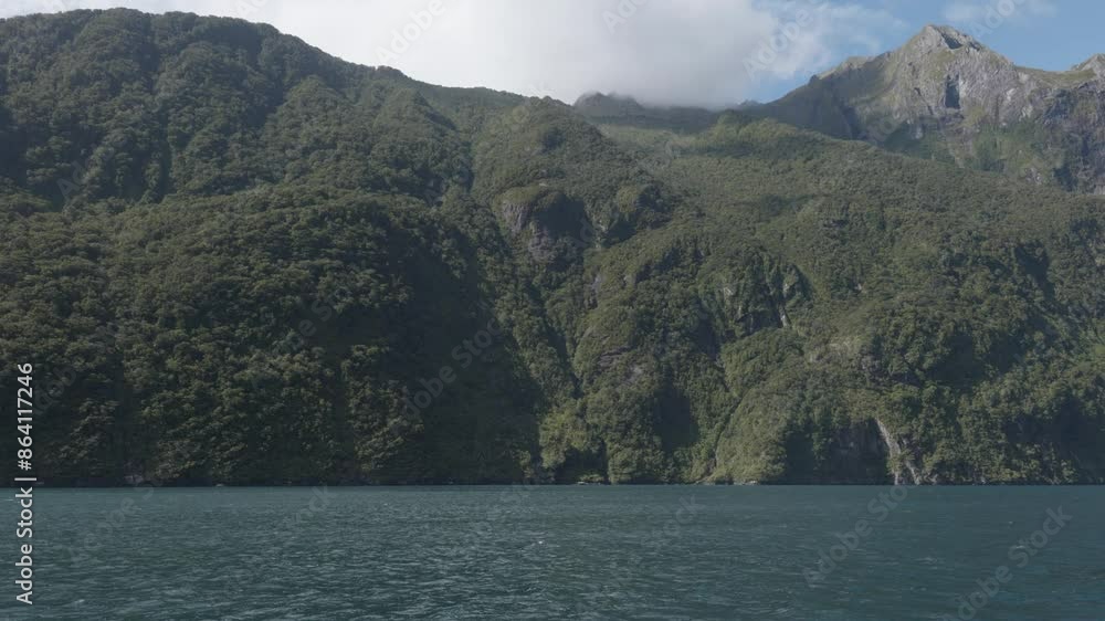 Wide view of the fiord and mountains from a boat during a sunny summer day in Milford Sound, Fiordland, New Zealand. Wide view of the fiord and mountains from a boat during a sunny summer day in Milford Sound, Fiordland, New Zealand.