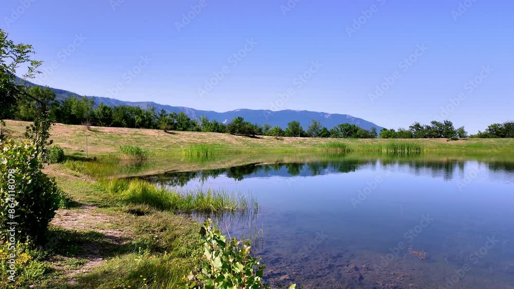 A tranquil lake reflecting the surrounding mountains and vegetation in a scenic Crimean landscape.