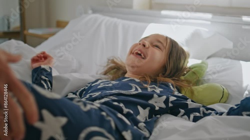 Mom tickling overjoyed toddler at bed closeup. Laughing little girl having fun photo