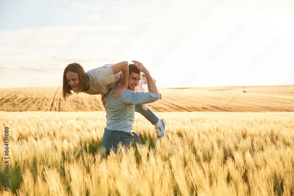 Having fun, man is holding woman. Lovely beautiful couple are together on the agricultural field Having fun, man is holding woman. Lovely beautiful couple are together on the agricultural field