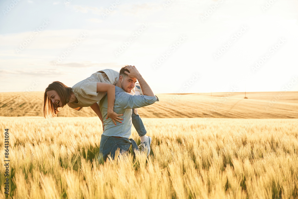 Having fun, man is holding woman. Lovely beautiful couple are together on the agricultural field Having fun, man is holding woman. Lovely beautiful couple are together on the agricultural field