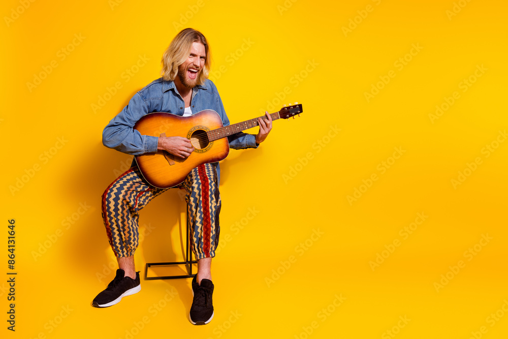 Fototapeta premium Full body photo of attractive young man play acoustic guitar singing dressed stylish denim clothes isolated on yellow color background