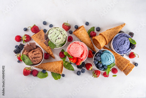 Fotografie Colorful bright ice cream on bowls, with waffle cones and berries, on white background