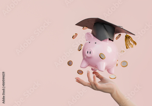 Pink Piggy Bank with Graduation Cap and Coins in Hand on Pink Background