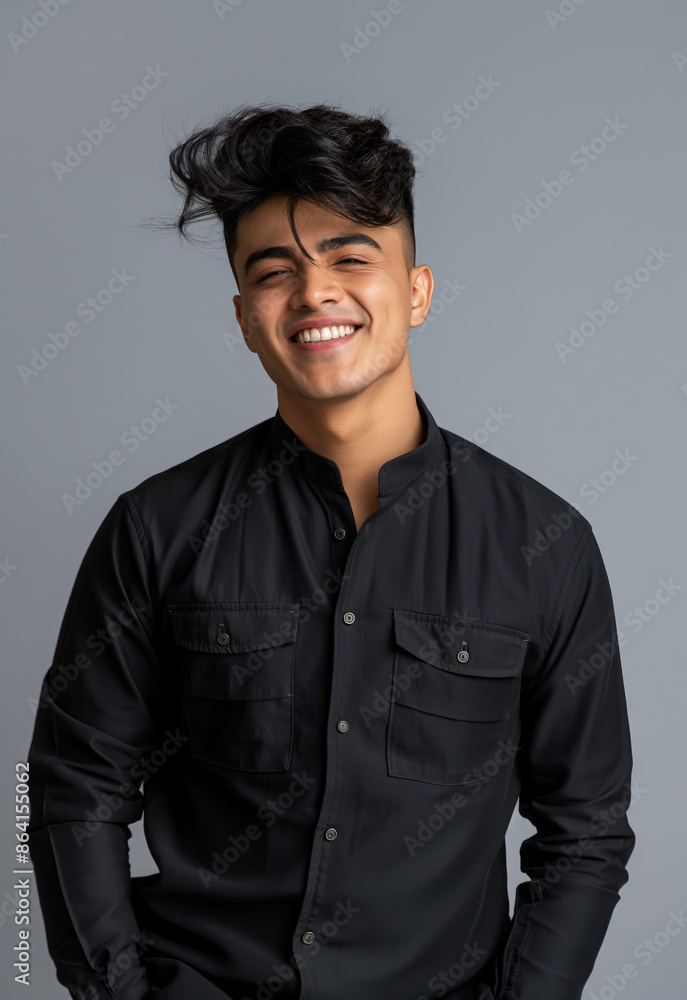 Obraz premium A young and handsome Indian male model in his early 20s, smiling at the camera, wearing a high collar colorful shirt, in a head and shoulder studio portrait with a light grey background